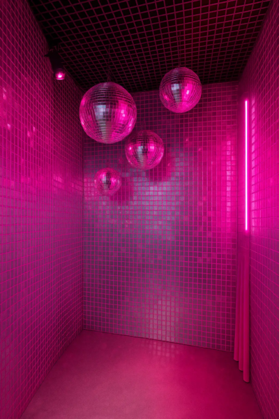 Cabine de photobooth coréen KONEO : décor “Cabine Miroir Disco” — parois carrelées réfléchissantes, lumière néon rose et boules à facettes suspendues. Un décor spectaculaire pour photos, clips et créations artistiques à l’esthétique disco-futuriste.