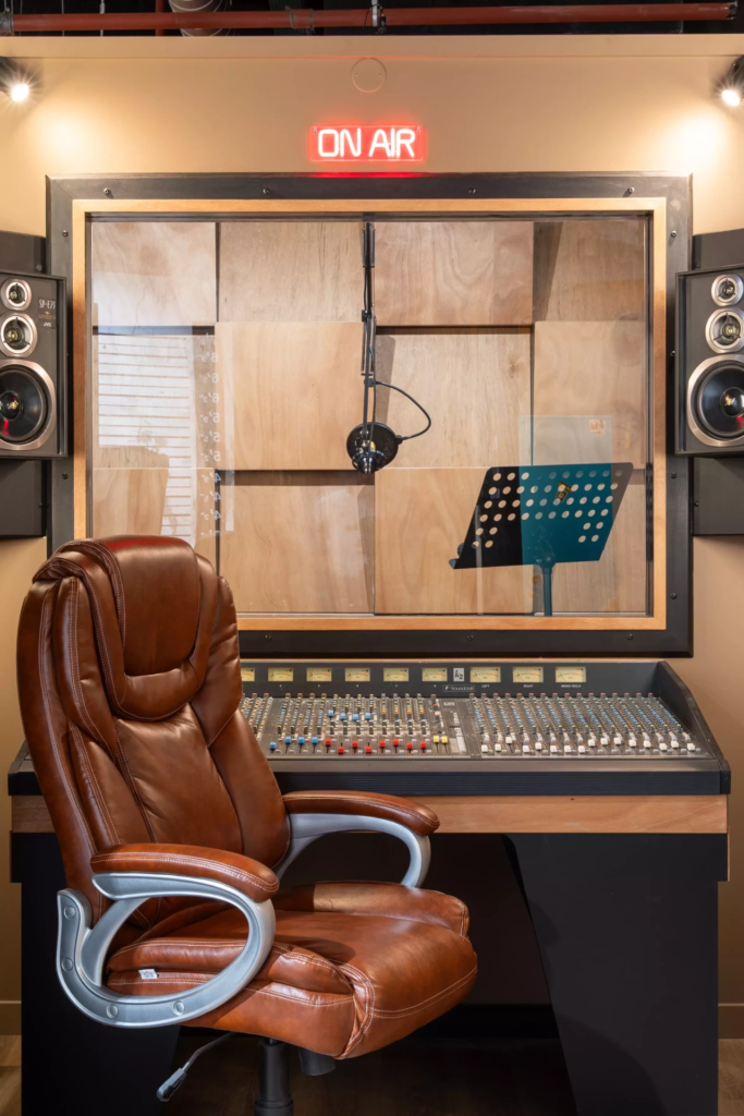 Décor de studio xd’enregistrement professionnel avec cabine de prise de son, console audio, microphone suspendu et ambiance inspirée de l’univers de la musique et du podcast