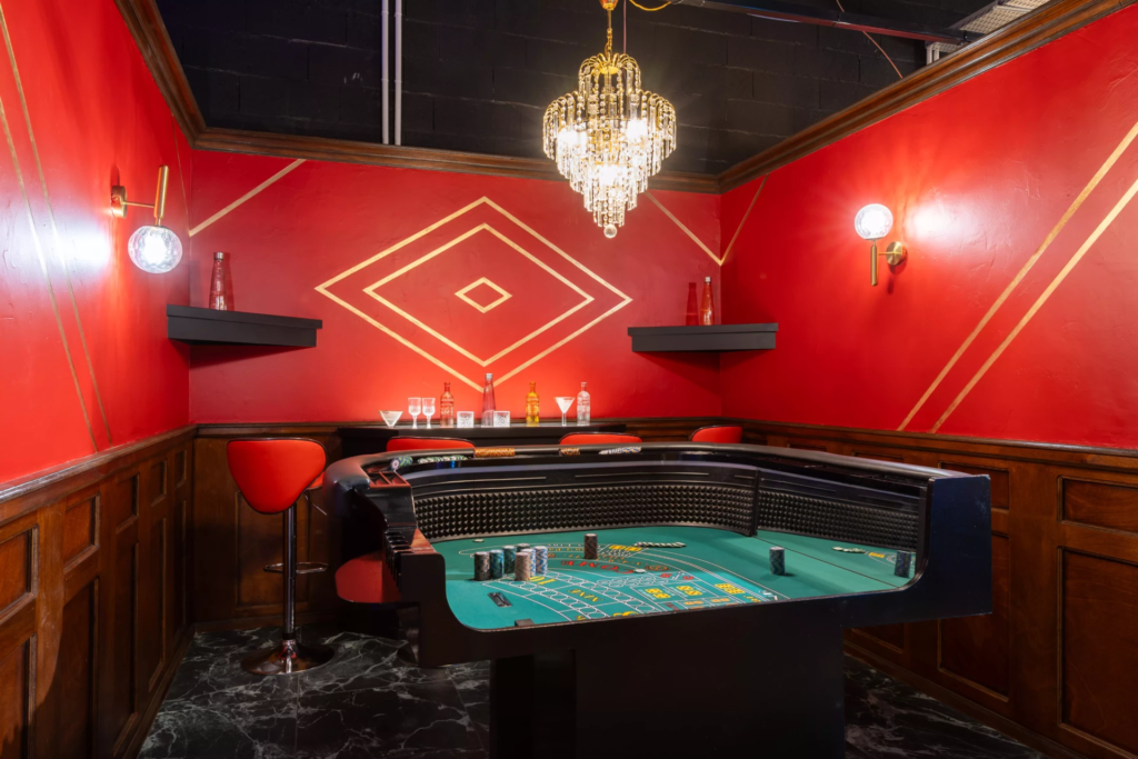 Décor casino élégant avec table de jeu professionnelle, ambiance feutrée, lustre raffiné, boiseries sombres et univers inspiré des casinos de Las Vegas et Monte-Carlo.