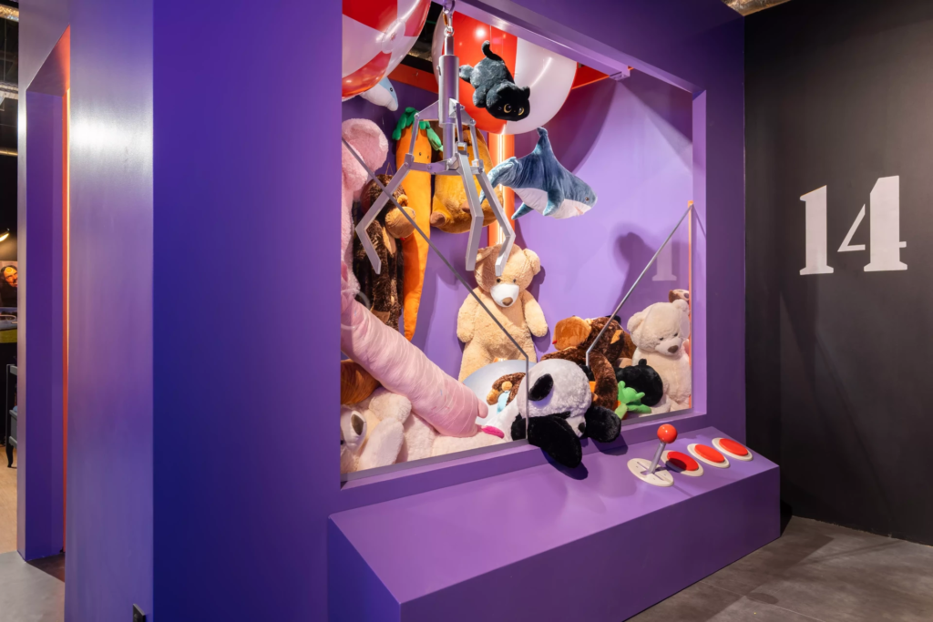 Décor inspiré d’une machine à pince géante remplie de peluches colorées, recréant l’univers des salles d’arcade et des fêtes foraines pour photos originales.