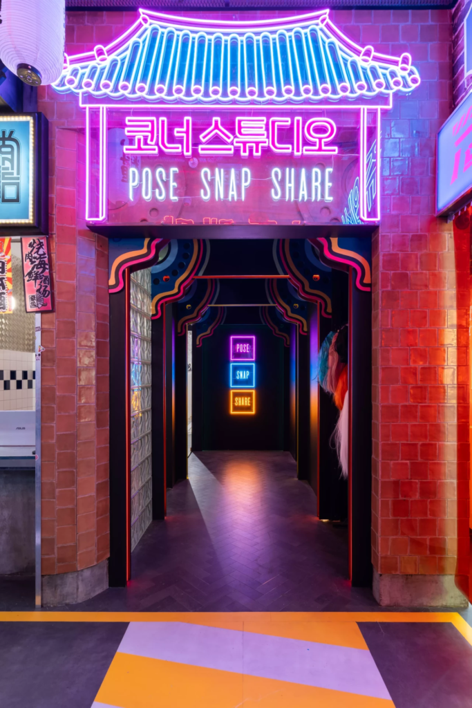 Passage immersif marqué par une arche lumineuse inspirée de l’architecture asiatique contemporaine, créant une transition spectaculaire vers les espaces photo.