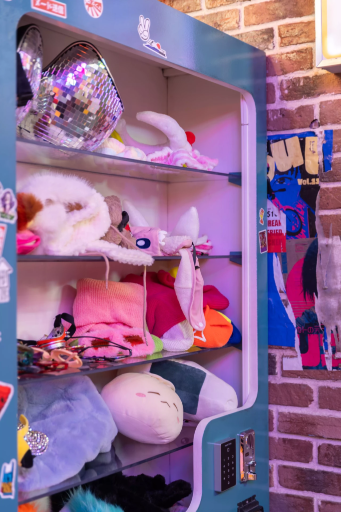 Décor de rue coréenne avec casier d’accessoires photo, peluches, vêtements et ambiance K-culture immersive inspirée des photobooths coréens modernes.