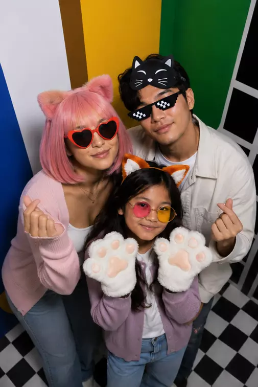 Famille posant dans le photobooth Pop de KONEO Studio à Paris avec accessoires colorés.