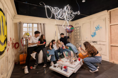 Groupe de 6 jeunes adultes (hommes et femmes) en train de se prendre en photo dans le décor imersif "Hangover" de KONEO Studio, à l'occasion d'un anniversaire