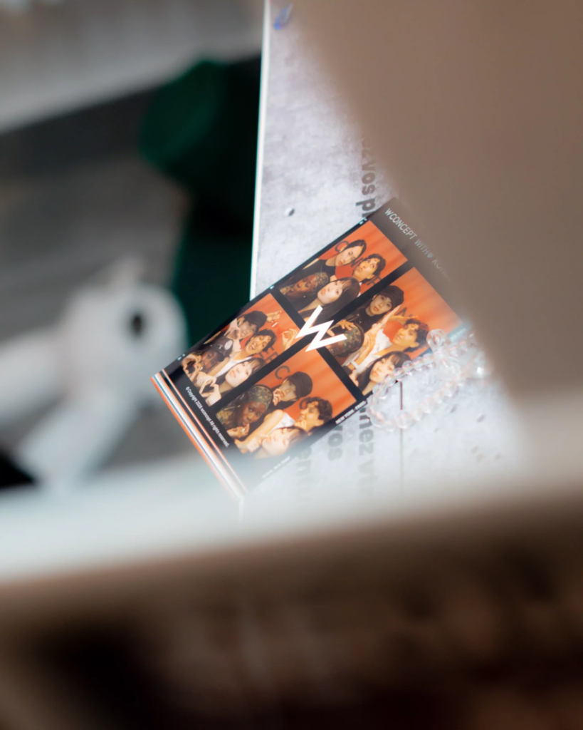Texte alternatif : Gros plan sur une bande de photos imprimée par un photomaton, montrant plusieurs portraits de groupe sur fond orange. Posé sur la machine et photographié avec une faible profondeur de champ, le tirage met en valeur le souvenir physique et instantané créé à l’issue de l’expérience photo.